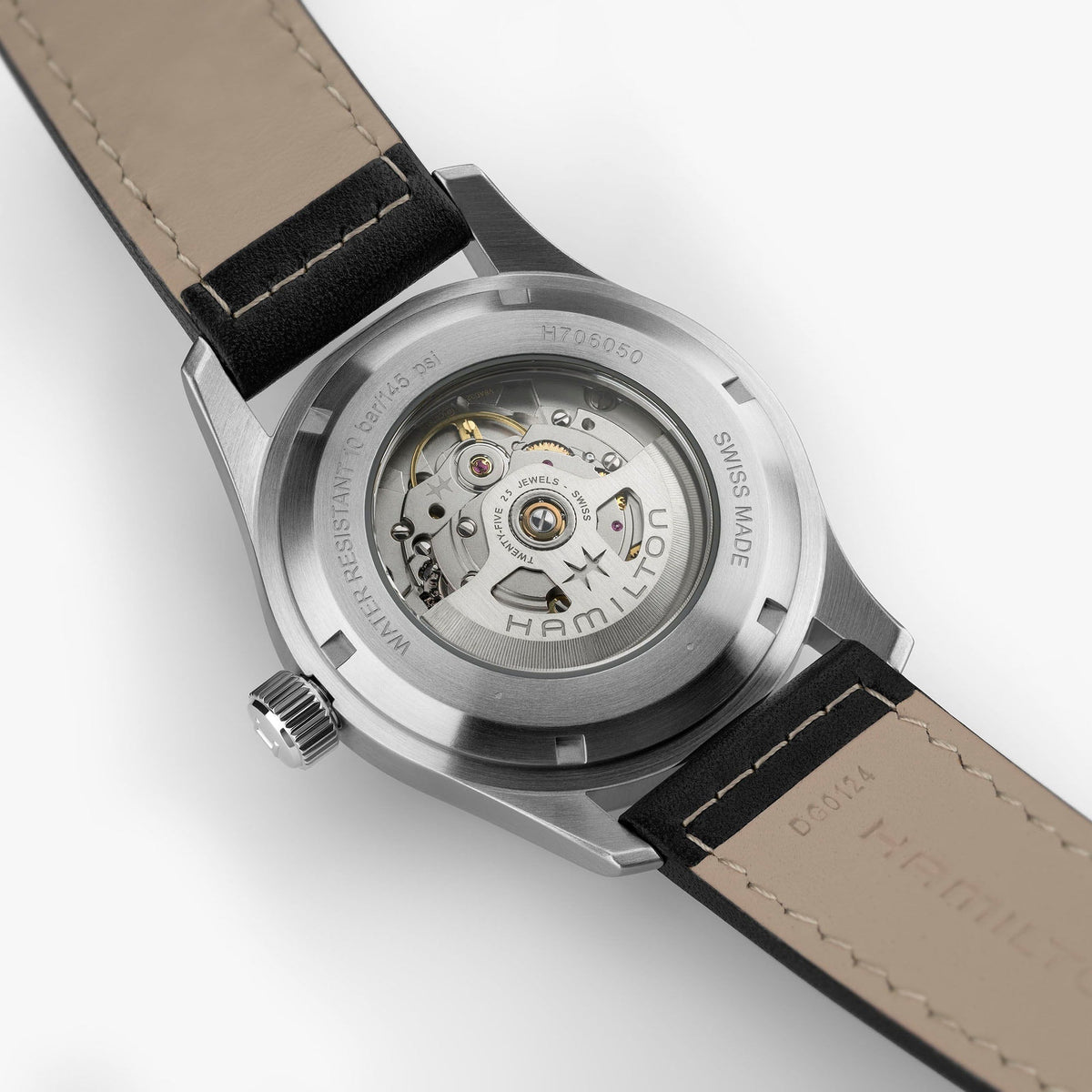 Close-up of the Hamilton Watch Khaki Field Auto 42mm’s transparent case back, revealing the inner automatic movement and mechanical calibre. The leather strap and engraved details around the case are also visible, showcasing its military watch heritage.