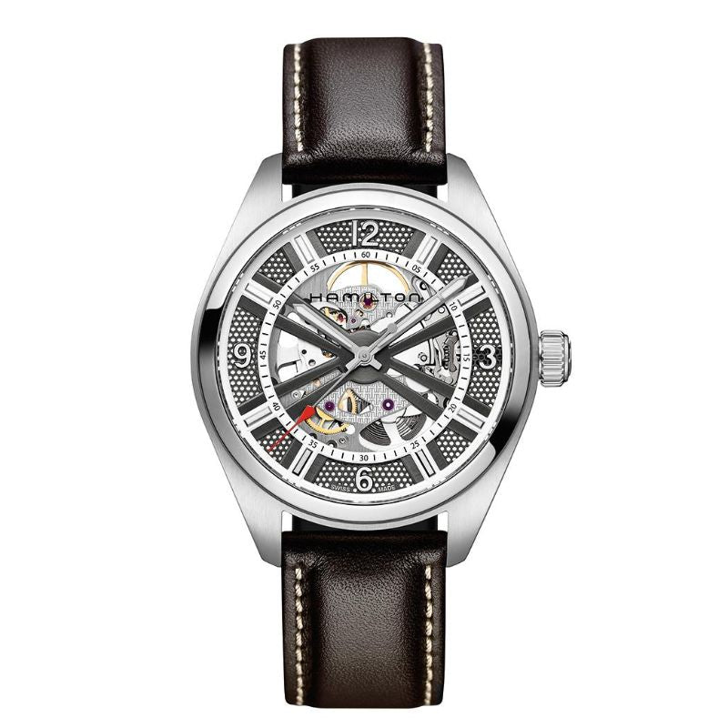 The Hamilton Khaki Field Skeleton Auto 42mm Watch by Hamilton Watch is crafted with a silver hue and includes a black leather strap. It showcases visible gears through its partially open dial, highlighting the detailed automatic movement. The hour markers are white, while the watch hands are silver.