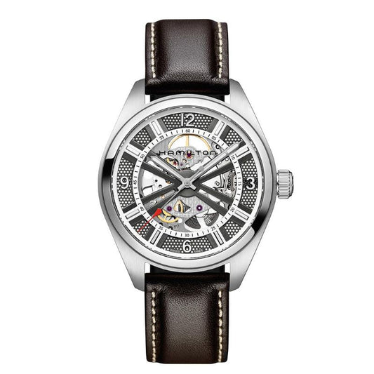 The Hamilton Khaki Field Skeleton Auto 42mm Watch by Hamilton Watch is crafted with a silver hue and includes a black leather strap. It showcases visible gears through its partially open dial, highlighting the detailed automatic movement. The hour markers are white, while the watch hands are silver.