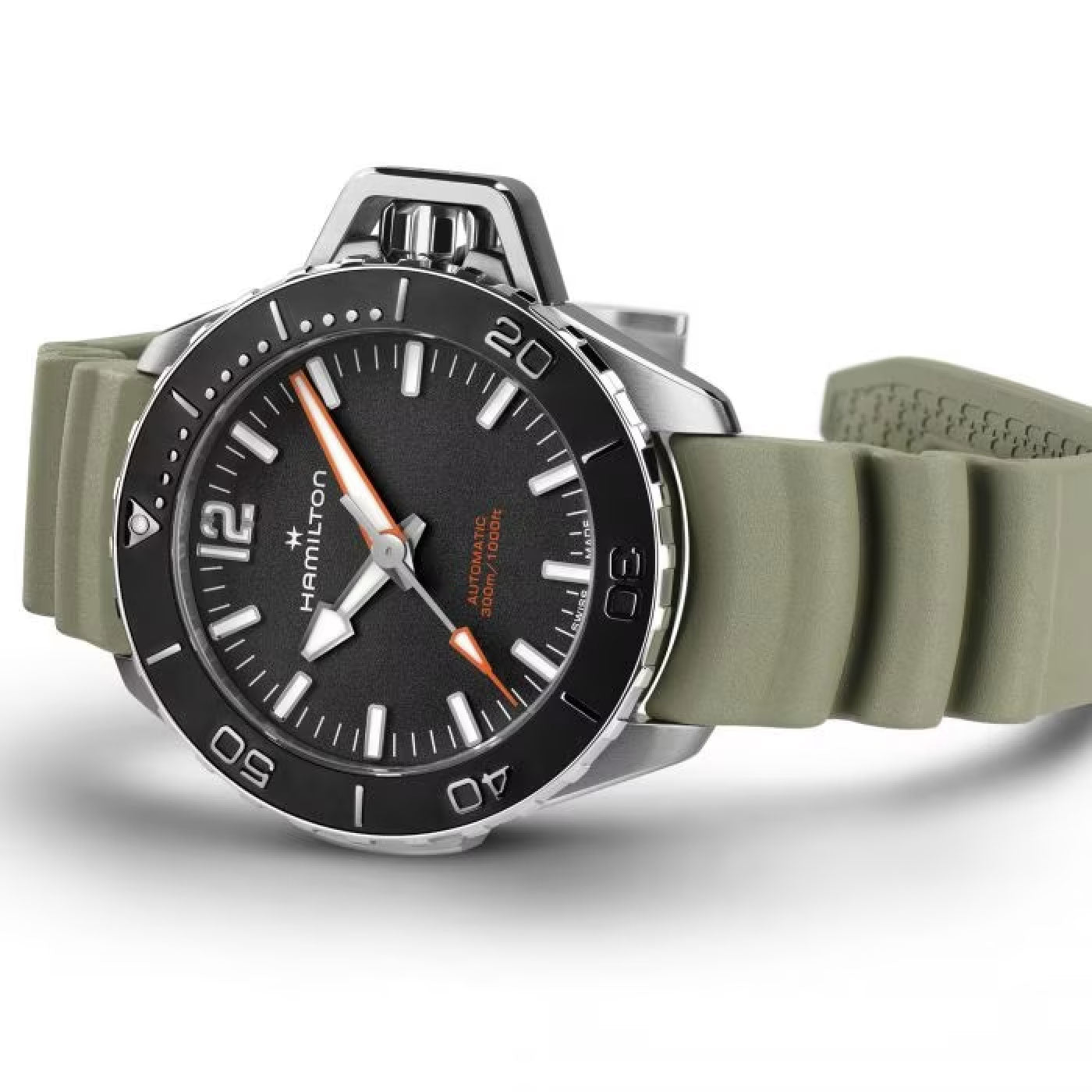 A close-up of the Hamilton Khaki Navy Frogman Auto 41mm Watch features a black dial, white hour markers, and a rotating bezel with minute markers. The watch showcases a silver case paired with an olive green rubber strap, with the Hamilton Watch brand name prominently visible on the dial.