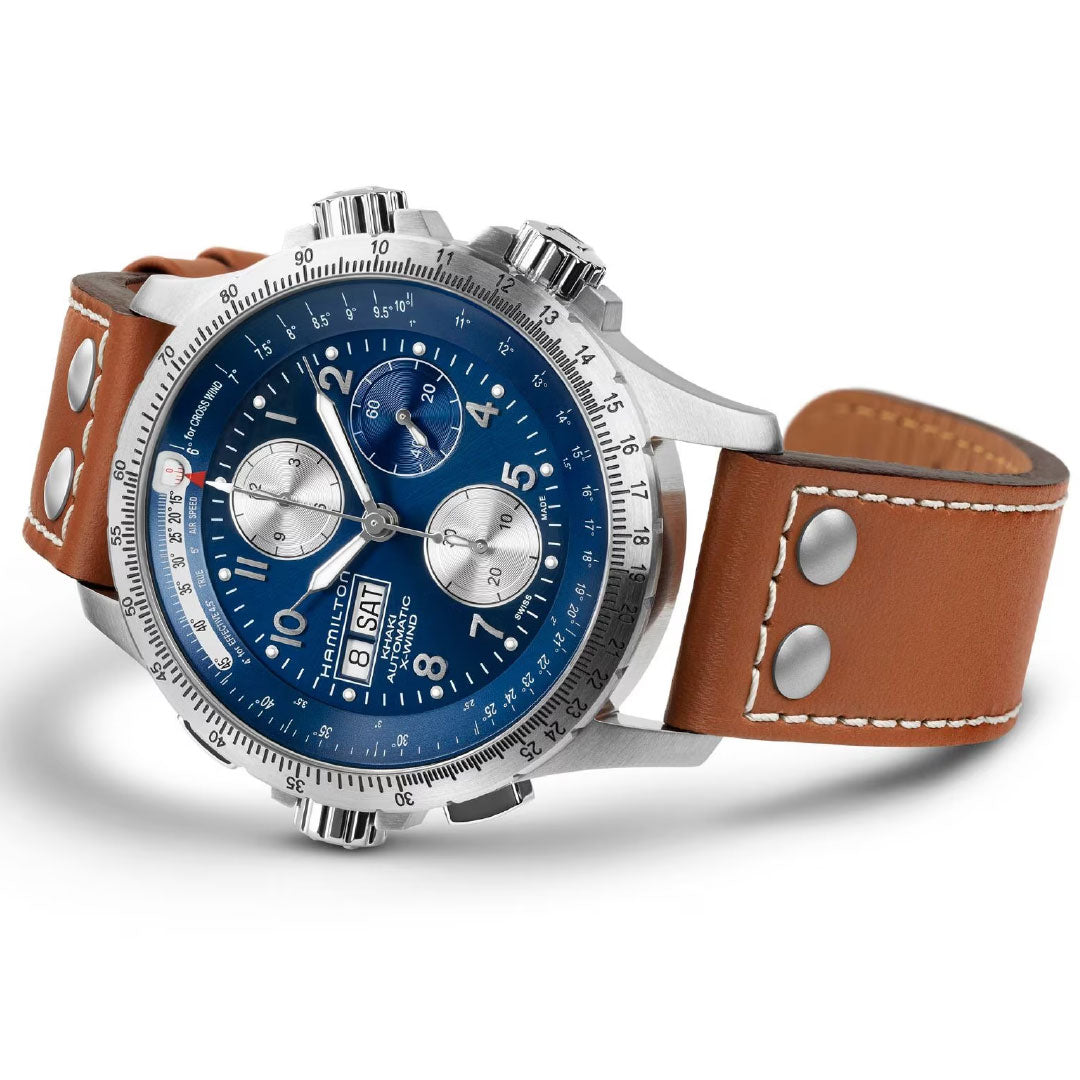 The Hamilton Khaki Aviation X-Wind Auto Chrono 44mm by Hamilton Watch features a stainless steel case, blue dial with three subdials, automatic chronograph, day/date display, and a brown leather strap with white stitching and metal accents.