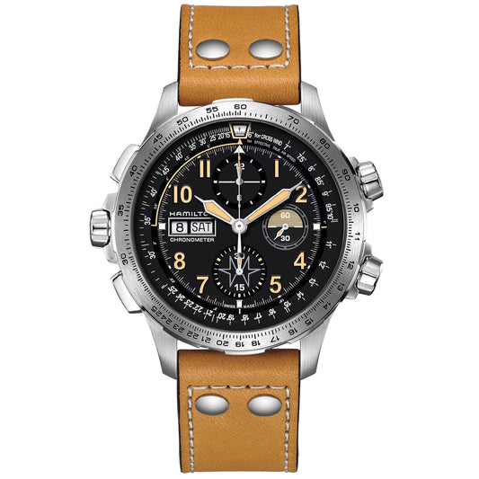 The Hamilton Khaki Aviation X-Wind Day Date Auto Chrono 45mm Watch by Hamilton Watch boasts a stainless steel case and a black dial with multiple subdials, day-date display, and tachymeter scale. It is distinguished by orange numerals, enhanced by a chronograph movement, and paired with a tan leather strap adorned with metal rivets.