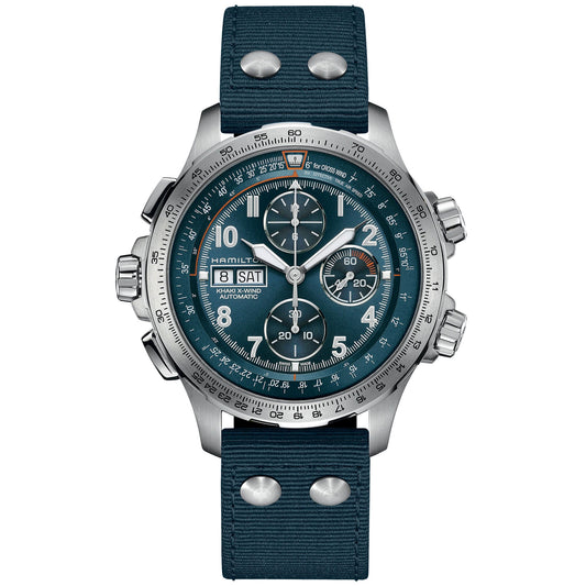 Introducing the Hamilton Khaki Aviation X-Wind Auto Chrono 45mm Watch: a stunning timepiece by Hamilton Watch, featuring a silver chronograph design with a unique teal dial. It showcases three subdials for day and date functions, alongside an automatic chronograph and tachymeter scale. The watch is elegantly complemented by a dark blue strap adorned with silver rivets, while silver hour markers and hands accentuate its sophisticated aesthetic.