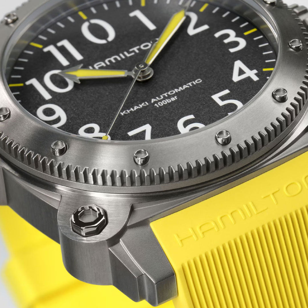 Close-up of the Hamilton Khaki Navy BeLow Zero Auto Titanium 46mm Watch by Hamilton Watch, featuring a black dial with large white numerals, yellow accents, a brushed titanium case, and a textured yellow strap embossed with "HAMILTON".