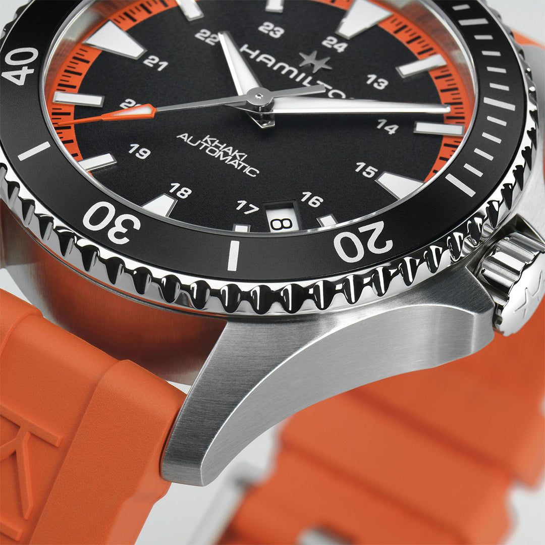 Close-up of the Hamilton Watch Khaki Navy Scuba Auto 40mm, featuring a tangerine orange rubber strap, black bezel and dial with white and orange hour markers, white hands, and a silver case with textured crown.
