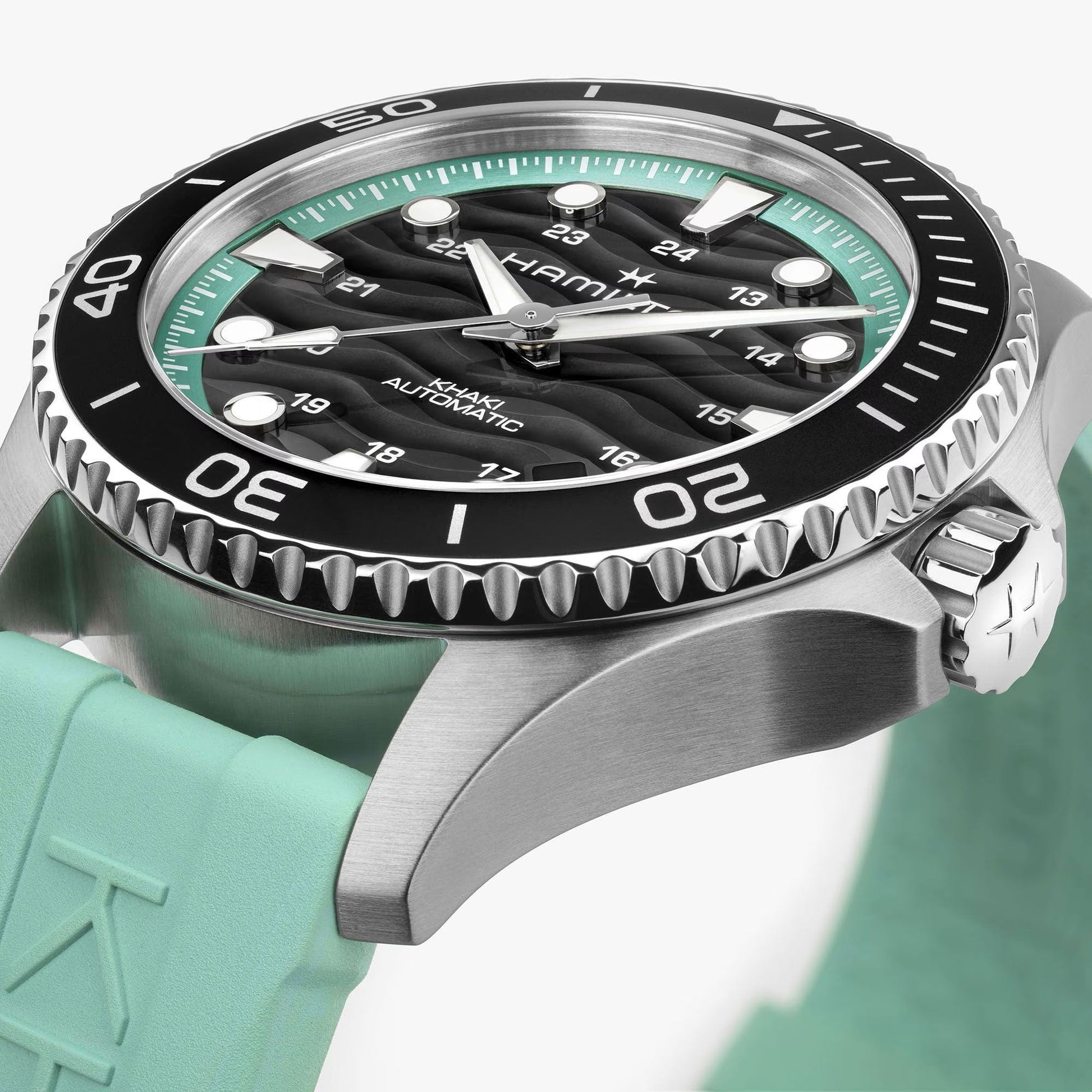A close-up of the 40mm Hamilton Khaki Navy Scuba Auto by Hamilton Watch, featuring a black and silver bezel, wavy black dial, luminous markers, light turquoise rubber strap, and a crown embossed with the "H" logo.