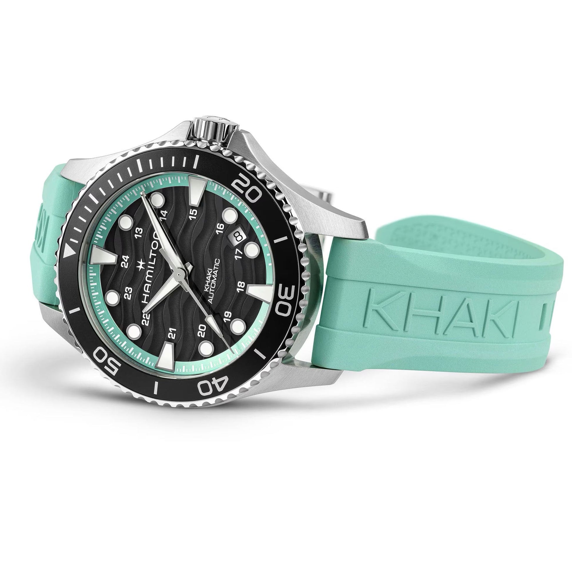 The Hamilton Khaki Navy Scuba Auto 40mm Watch by Hamilton Watch features a silver and black case, textured black dial, and mint green rubber strap with "KHAKI" embossed, shown resting on its side.