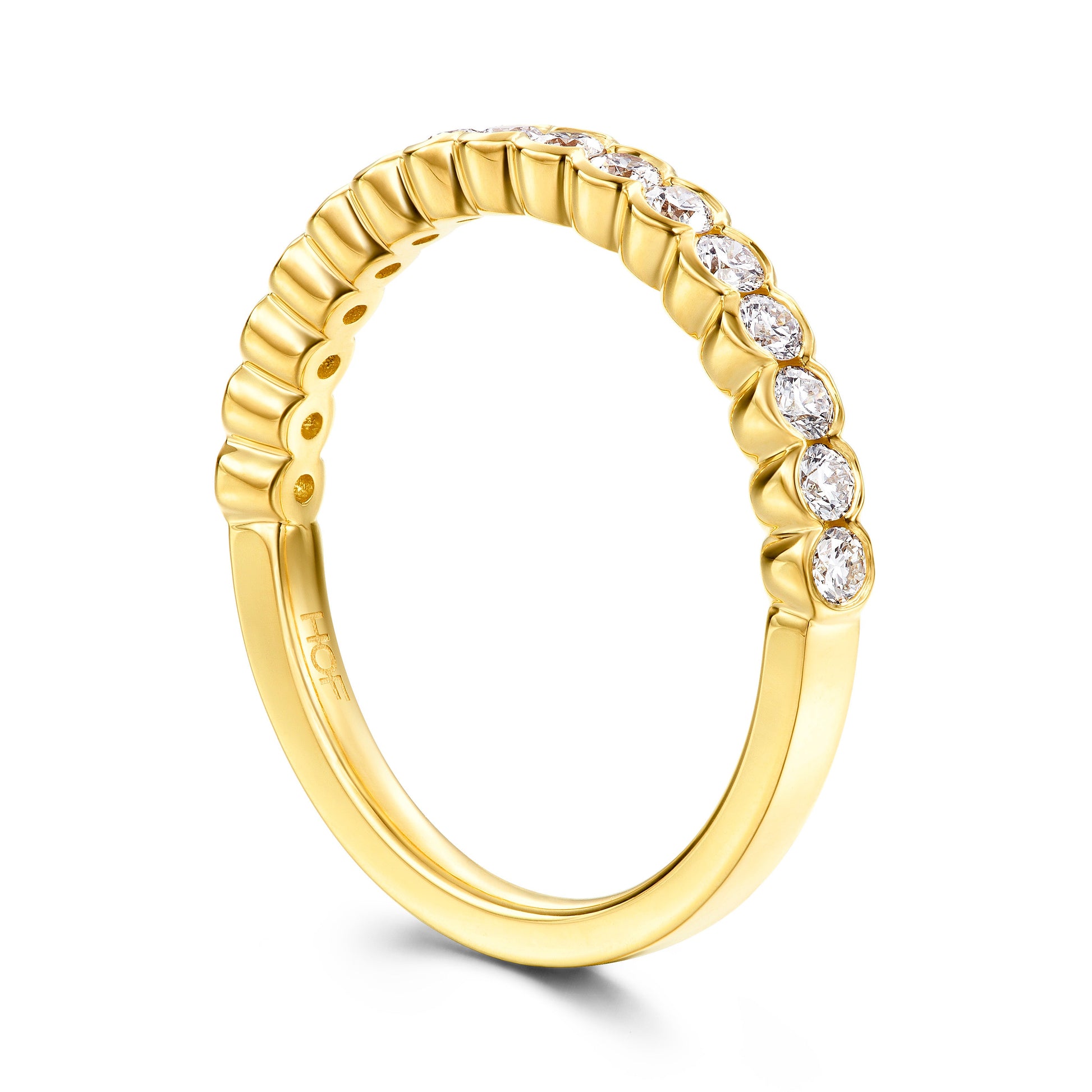 The Hearts On Fire Isabelle 18K Yellow Gold Bezel Round Brilliant Diamond Anniversary Ring showcases a series of round, clear diamonds elegantly set along the top half. Its smooth finish and subtly ridged design enhance its elegance, offering a perfect choice for those seeking timeless beauty.