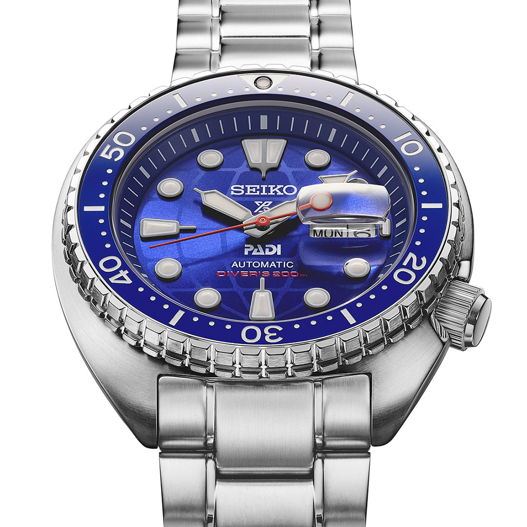 A close-up of the Seiko Prospex Sea 60th Anniversary Limited Edition Automatic 45mm Watch PADI, featuring a blue dial, silver bezel, and stainless steel band by Seiko. The day and date window reads “MON 15.”.