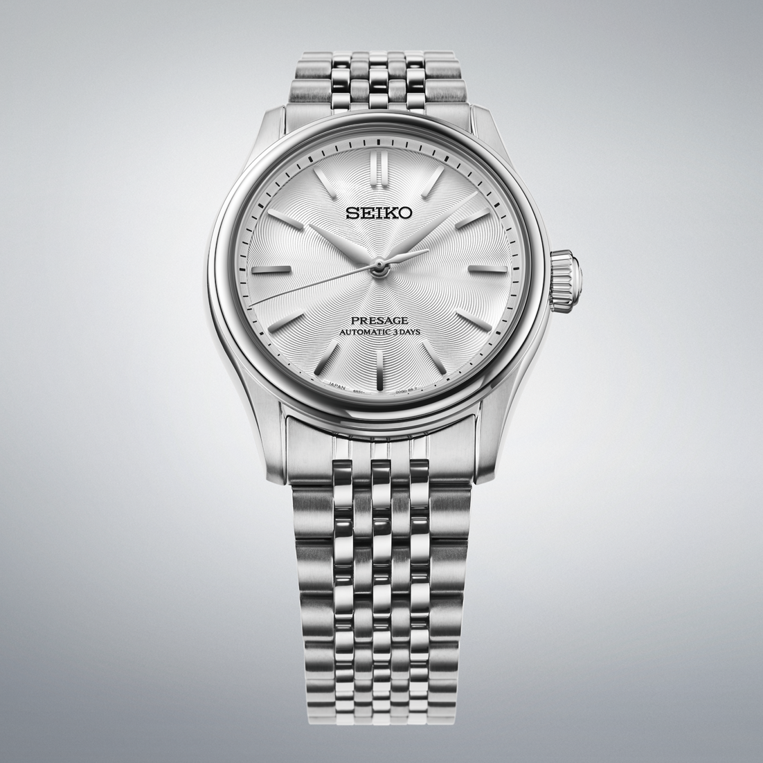 A silver-tone Seiko Presage Classic Series Automatic With Manual Winding 38mm Watch featuring a textured, circular-patterned white dial and a multi-link metal bracelet.