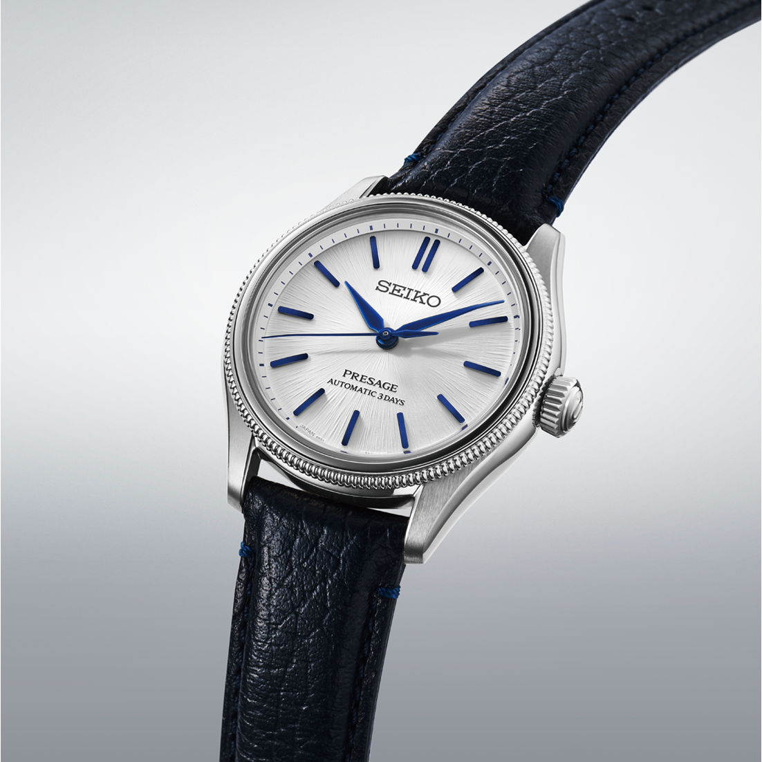 A silver-tone Seiko Presage Classic Series 145th Anniversary Limited Edition Automatic With Manual Winding 36mm Watch with a white textured dial, blue hands and markers, and a dark leather strap.