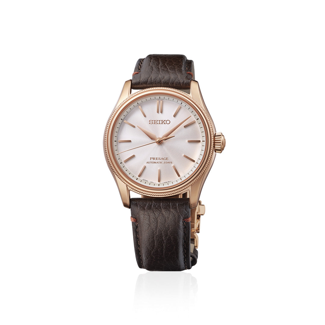 A Seiko Presage Classic Series Tomioka Silk Promotion Organization Automatic 38mm Watch, limited to 2,000 pieces, featuring a white dial, gold-tone case, gold hour markers and hands, and a brown leather strap, displayed on a white background.