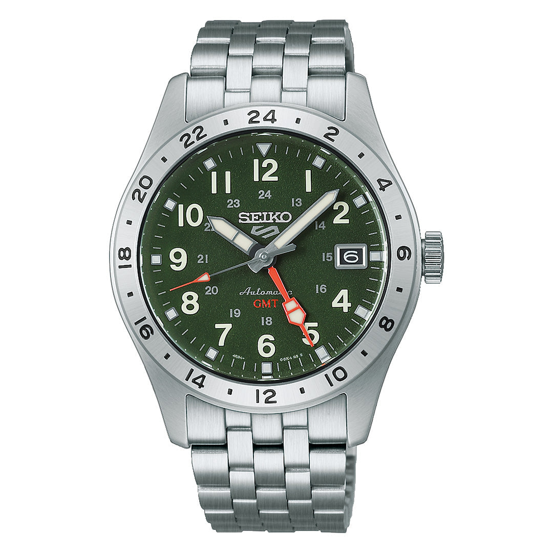 The Seiko 5 Sports Field Series GMT Automatic 39.3mm Watch by Seiko features a green dial with silver hour markers, a red GMT hand, and a stainless steel bracelet. This automatic timepiece is equipped with a bezel marked with 24-hour numerals and has a date window located at the 3 o’clock position.
