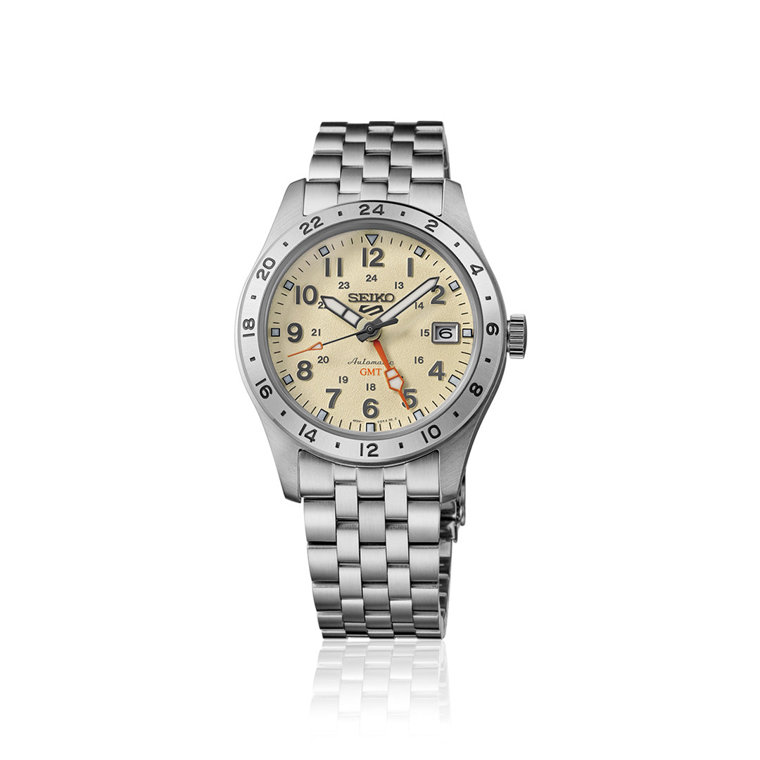 The Seiko 5 Sports Field Series GMT Automatic 39.3mm Watch by Seiko features a stainless steel case and bracelet, a beige dial with black hour markers, an orange GMT hand, and a date window at 3 o’clock. Displayed on a white background, this timepiece blends durability with refined design.