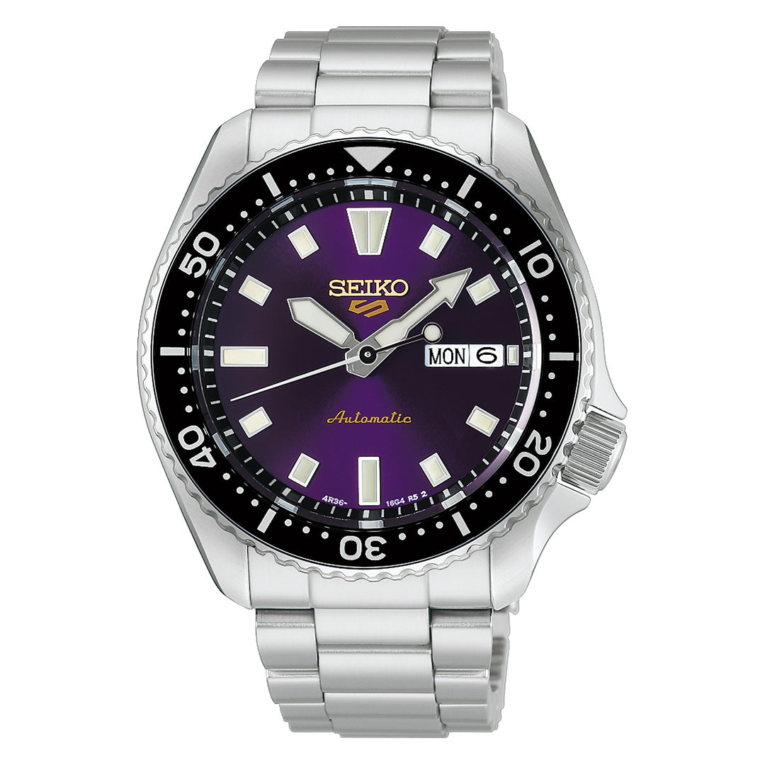 A Seiko 5 Sports SKX Series Limited Edition Automatic 42.5mm watch featuring a silver metallic band, black bezel, and purple dial. The face displays white hour markers, a day-date window at the 3 o’clock position, and “Automatic” written in gold above the 6 o’clock mark.