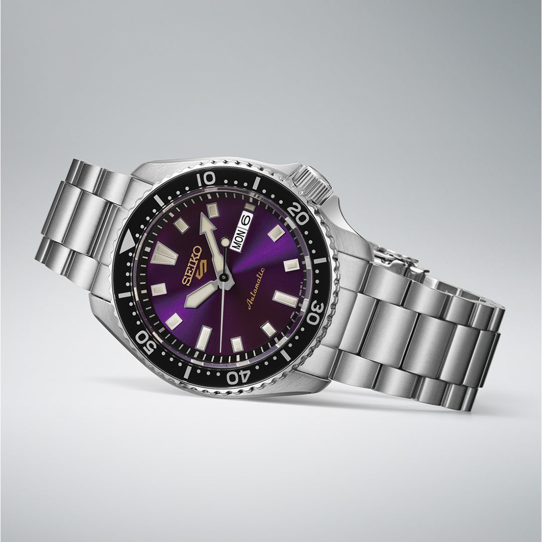 The Seiko 5 Sports SKX Series Limited Edition Automatic 42.5mm watch features a stainless steel case, a striking purple gradient dial with silver hour markers, a black bezel, and a day-date display, displayed at an angle on a light gray background.