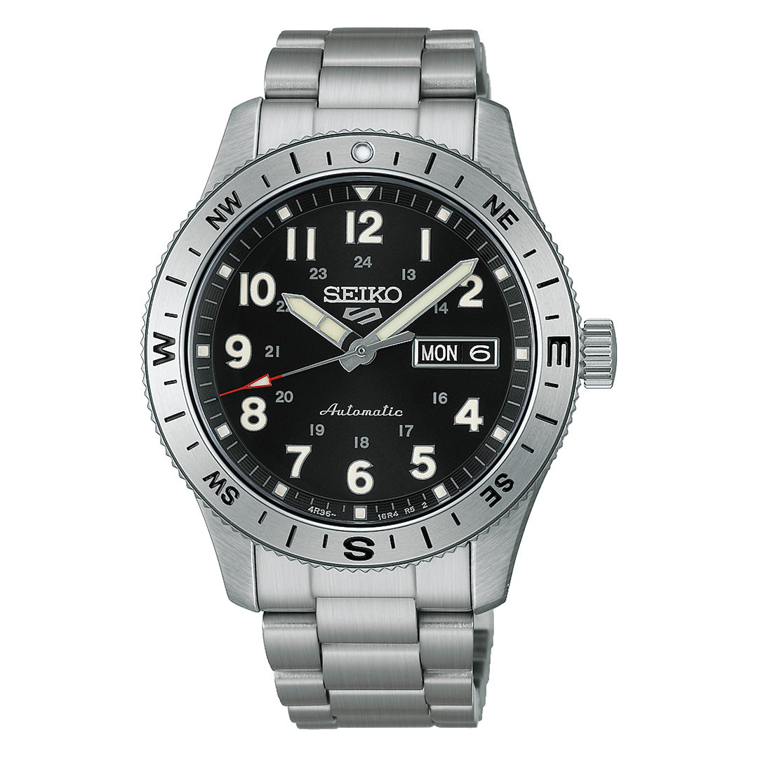 The Seiko 5 Sports Field Series Automatic 41mm Watch by Seiko features a durable stainless steel case and matching metal bracelet, complemented by a striking black dial with silver markers illuminated by LumiBrite for exceptional visibility. This timepiece also offers day and date display, 24-hour numerals, and a compass bezel for enhanced functionality.