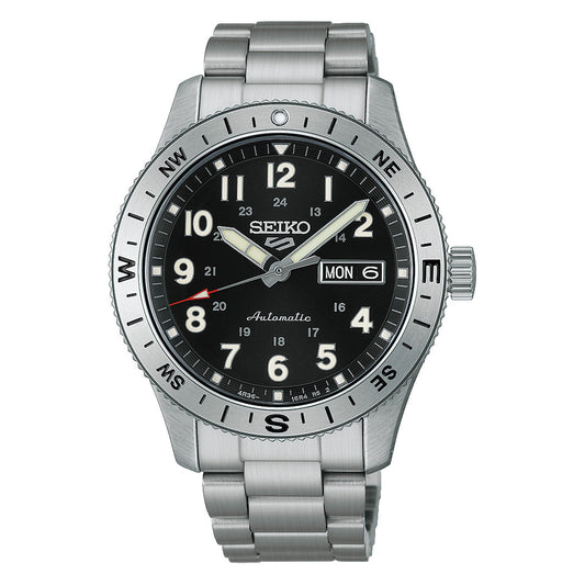 The Seiko 5 Sports Field Series Automatic 41mm Watch by Seiko features a durable stainless steel case and matching metal bracelet, complemented by a striking black dial with silver markers illuminated by LumiBrite for exceptional visibility. This timepiece also offers day and date display, 24-hour numerals, and a compass bezel for enhanced functionality.