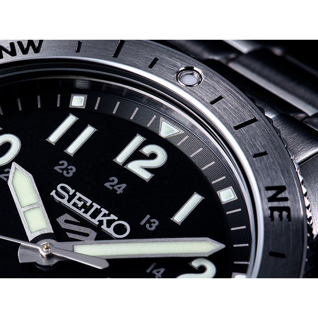 Close-up of the Seiko 5 Sports Field Series Automatic 41mm Watch by Seiko, featuring LumiBrite luminous hands, bold numerals, and a brushed metal bezel with compass markings (NW, N, NE), paired with a sleek metal bracelet.