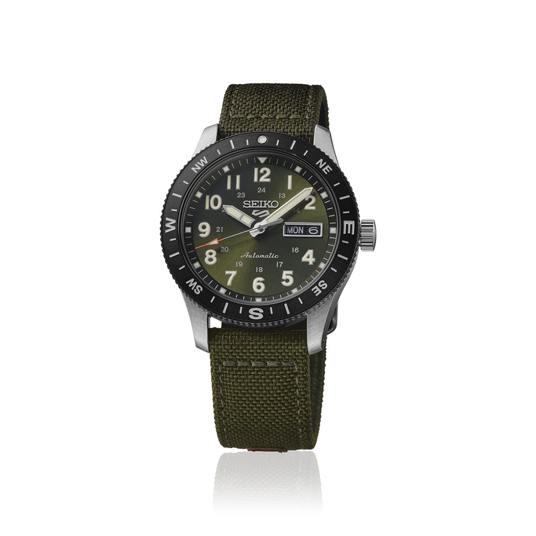 The Seiko 5 Sports Field Series Automatic 41mm Watch by Seiko features a rugged olive green nylon strap, a black rotating bezel, and a green dial with white numerals, day and date display. The watch hands and markers are white with LumiBrite luminescent accents for enhanced visibility.