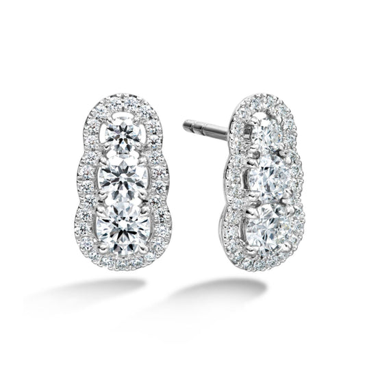 Introducing the Hearts On Fire Aurora Drop Earrings: Crafted by the renowned brand, these stunning earrings showcase three rows of round diamonds set in lustrous 18 karat white gold, outlined with a shimmering border of smaller diamonds. Displayed against a plain white background, they epitomize elegance.