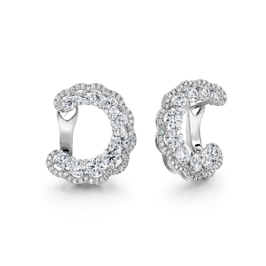 The Hearts On Fire Aurora Hoop Earrings are set against a white background, showcasing their elegant sparkle. Crafted with multiple round diamonds, they shine beautifully in 18 karat white gold or platinum, offering a timeless and luxurious appeal.