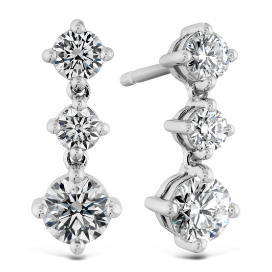 Discover the elegance of the Hearts On Fire Cascade Earrings, crafted in white gold and adorned with three round diamonds on each earring. The diamonds are set in a simple prong setting and arranged vertically, with sizes increasing from top to bottom, for maximum shine and reflection.