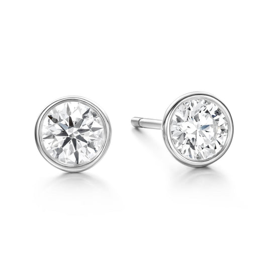 The Hearts On Fire Classic Bezel 18K White Gold Earrings, crafted by the renowned brand Hearts on Fire, are displayed on a plain white background. These luxurious pieces of jewelry feature sparkling, clear round diamonds set in a polished white gold bezel setting.