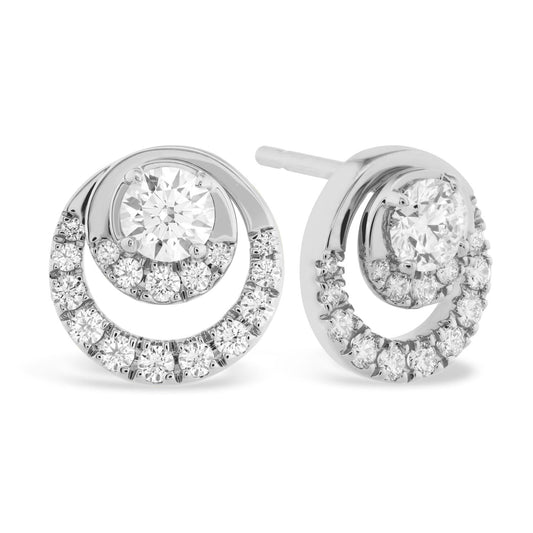 The Hearts On Fire Optima 18K White Gold Earrings by Hearts on Fire showcase a sophisticated design, featuring a central round-cut diamond encircled by a halo of smaller diamonds. The earrings are crafted from polished white gold and highlight two concentric circles that enhance the allure of the central stone.
