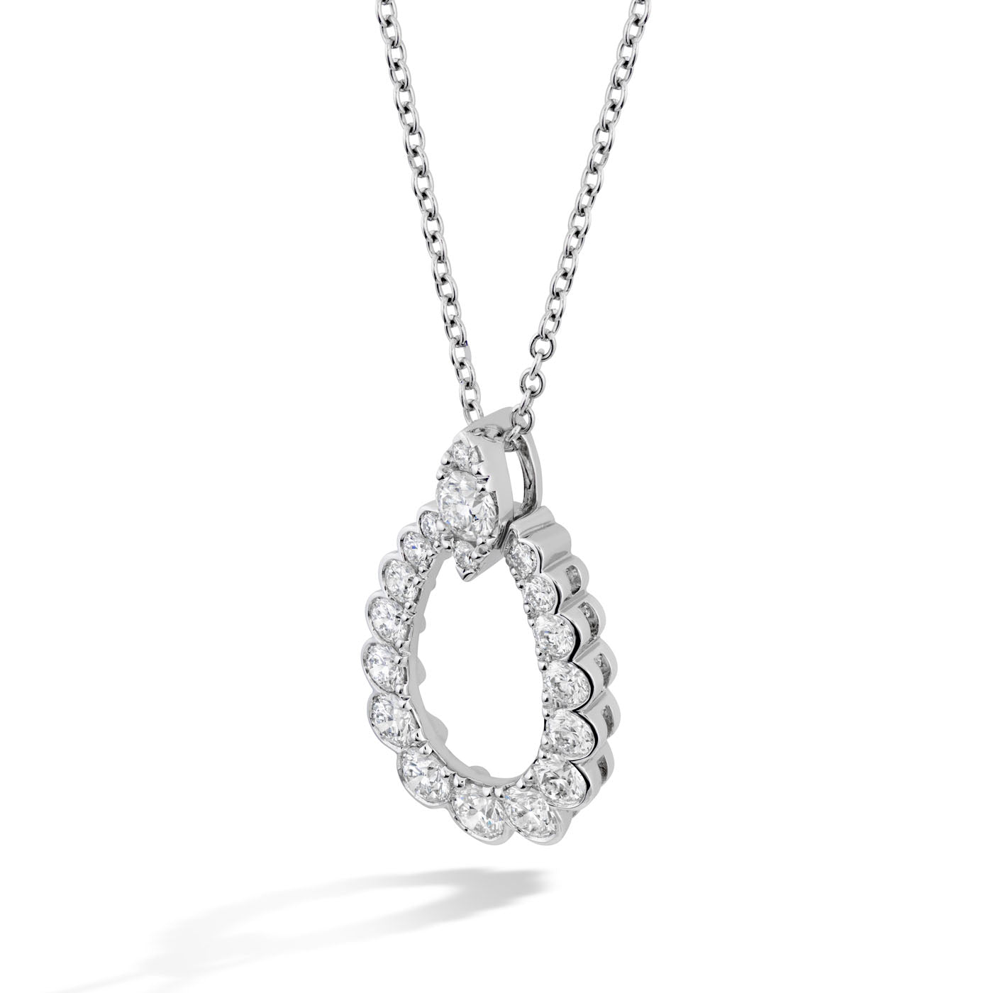 A Hearts On Fire Aerial 18K White Gold Teardrop Pendant necklace, featuring an oval design adorned with small round diamonds, hangs gracefully against a simple white background. Its luminous sparkle offers an exquisite enhancement to any outfit.