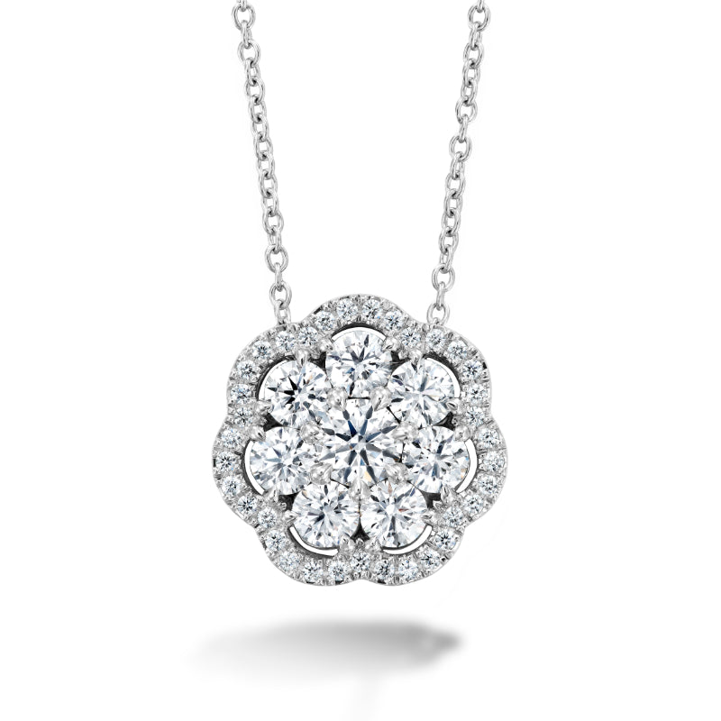 Introducing the Hearts On Fire Aurora Cluster Necklace, a stunning silver piece by Hearts on Fire. This necklace features a floral pendant embellished with sparkling white diamonds, encircled by a halo of smaller gems, all beautifully set on a fine chain.