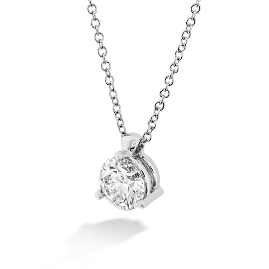 A close-up of the Hearts On Fire HOF Classic Solitaire Necklace by Hearts on Fire, featuring a single round diamond pendant secured in a classic four-prong setting. The pendant hangs gracefully from a delicate chain, showcasing its timeless design as the diamond catches the light and radiates brilliance against the white background.