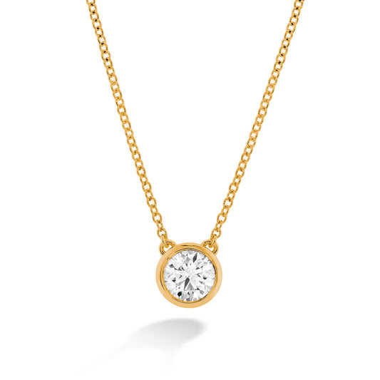 The Hearts On Fire Classic Bezel 18K Yellow Gold Pendant is a stunning necklace featuring a round diamond set in a bezel on an 18 Karat yellow gold chain. The elegant chain beautifully accentuates the diamond's brilliant, reflective surface against a white background.