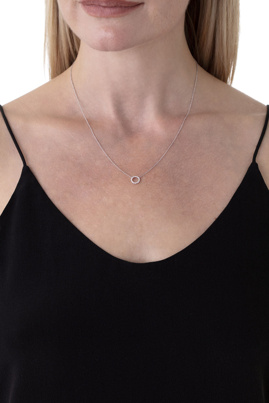 A woman in a black sleeveless top is showcasing the Hearts on Fire Signature Circle 18K White Gold Pendant, which glows elegantly against her light skin. The focus is on this delicate piece, set against a plain white background.