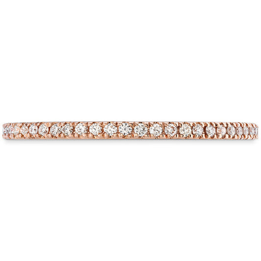 The Hearts On Fire Classic 18K Rose Gold Round Brilliant Diamond Eternity Ring by Hearts On Fire is a stunning wedding band crafted from 18 karat rose gold, adorned with an array of small, sparkling diamonds encircling the entire band.
