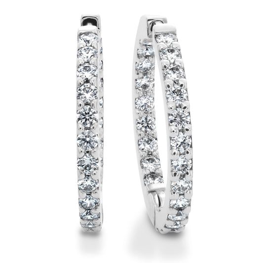 A pair of luxurious Hearts On Fire 18K White Gold Earrings showcases a stunning row of sparkling round diamonds along the outer edge of each hoop, elegantly catching the light against a pristine white background.