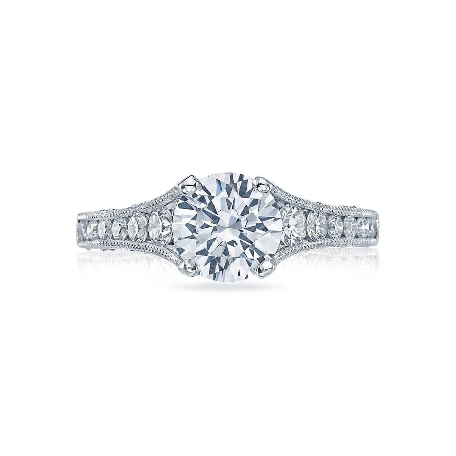 The Tacori Reverse Crescent engagement ring in 18K white gold features a prominent round brilliant diamond solitaire at its center, accented by smaller channel-set diamonds on the intricately detailed band. The elegant design is further enhanced by Tacori's signature crescent silhouettes.