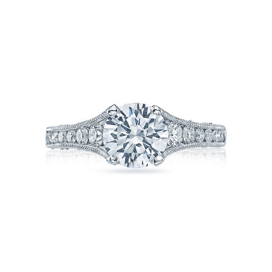The Tacori Reverse Crescent engagement ring in 18K white gold features a prominent round brilliant diamond solitaire at its center, accented by smaller channel-set diamonds on the intricately detailed band. The elegant design is further enhanced by Tacori's signature crescent silhouettes.