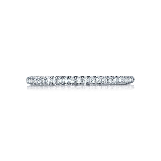A delicate, thin band featuring small, sparkling diamonds is centered against a white background. This Tacori Petite Crescent 18K White Gold Round Brilliant French Pavé Diamond Anniversary Ring highlights a continuous line of stones, showcasing its elegant and minimalist design.