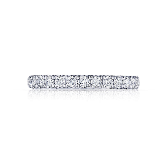 The Tacori Petite Crescent Platinum Round Brilliant Diamond Anniversary Ring features a continuous row of sparkling round diamonds set in a slender band. Reflected on a glossy white surface, it highlights the elegance and brilliance characteristic of Tacori engagement rings.