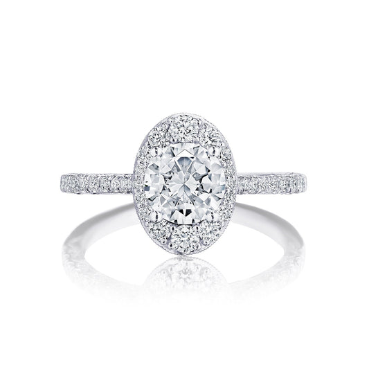 Introducing the Tacori Petite Crescent engagement ring, crafted in 18K white gold. This exquisite piece showcases a central round brilliant diamond halo setting, complemented by a diamond-studded crescent. The Cathedral-style band is beautifully adorned with tiny diamonds, enhancing the ring's elegance.
