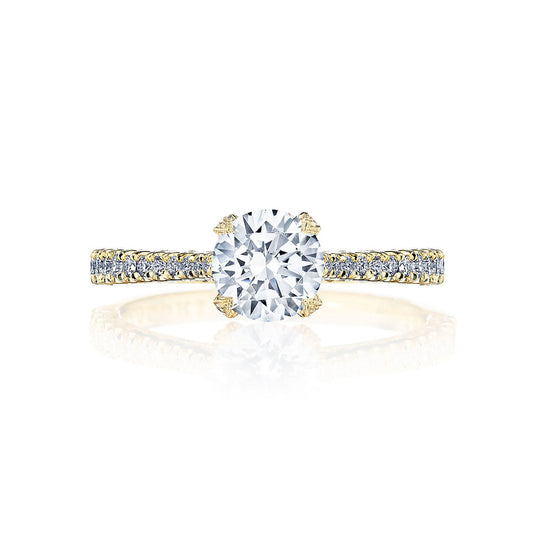 The Tacori Petite Crescent 18K Yellow Gold Round Brilliant Solitaire Semi Mount with Diamond Band Engagement Ring showcases a large round cut center diamond, expertly crafted by TACORI gemologists. The ring features a G color and VS clarity diamond on a cathedral foundation, accentuated by additional smaller diamonds on the band, all beautifully displayed against a white background.