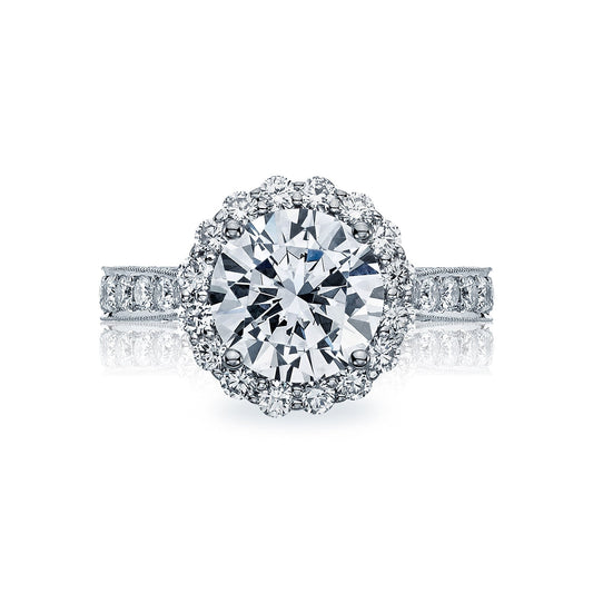 The Tacori Classic Crescent RoyalT Platinum Round Brilliant Semi Mount with Diamond Band and Halo Engagement Ring showcases an exquisite style with a large round center diamond, encircled by a halo of smaller diamonds. The band is adorned with additional diamonds, heightening the ring's luxurious and elegant design.
