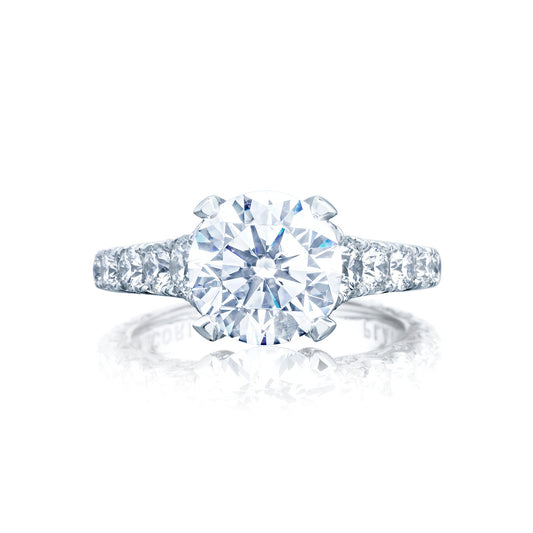 The Tacori Petite Crescent RoyalT engagement ring showcases a stunning round brilliant solitaire set on a platinum band with a cathedral foundation. Enhanced with G color diamonds and diamond-studded prongs, it creates a radiant display against a white background.