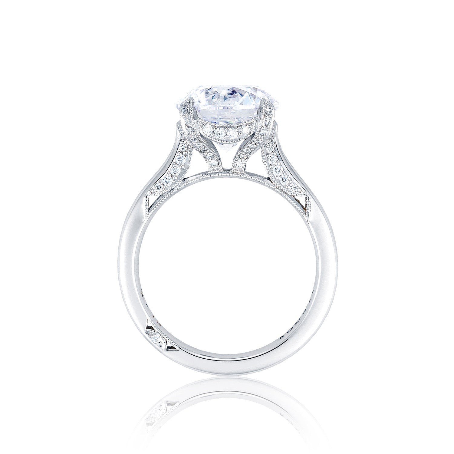 The Tacori Simply Tacori RoyalT Platinum Round Brilliant Solitaire Semi Mount Engagement Ring features an elaborate design with a prominent round diamond centerpiece, complemented by smaller diamonds adorning the band. Expertly crafted by TACORI gemologists, it is showcased against a white background.