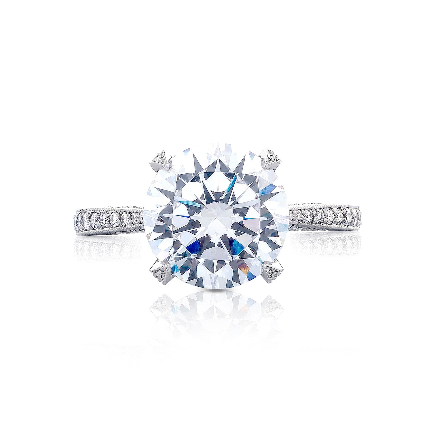 The Tacori Simply Tacori RoyalT engagement ring showcases a breathtaking round brilliant solitaire diamond set on a platinum band, accentuated by smaller diamonds. Its central placement emphasizes the intricate details, capturing the timeless elegance of diamonds.