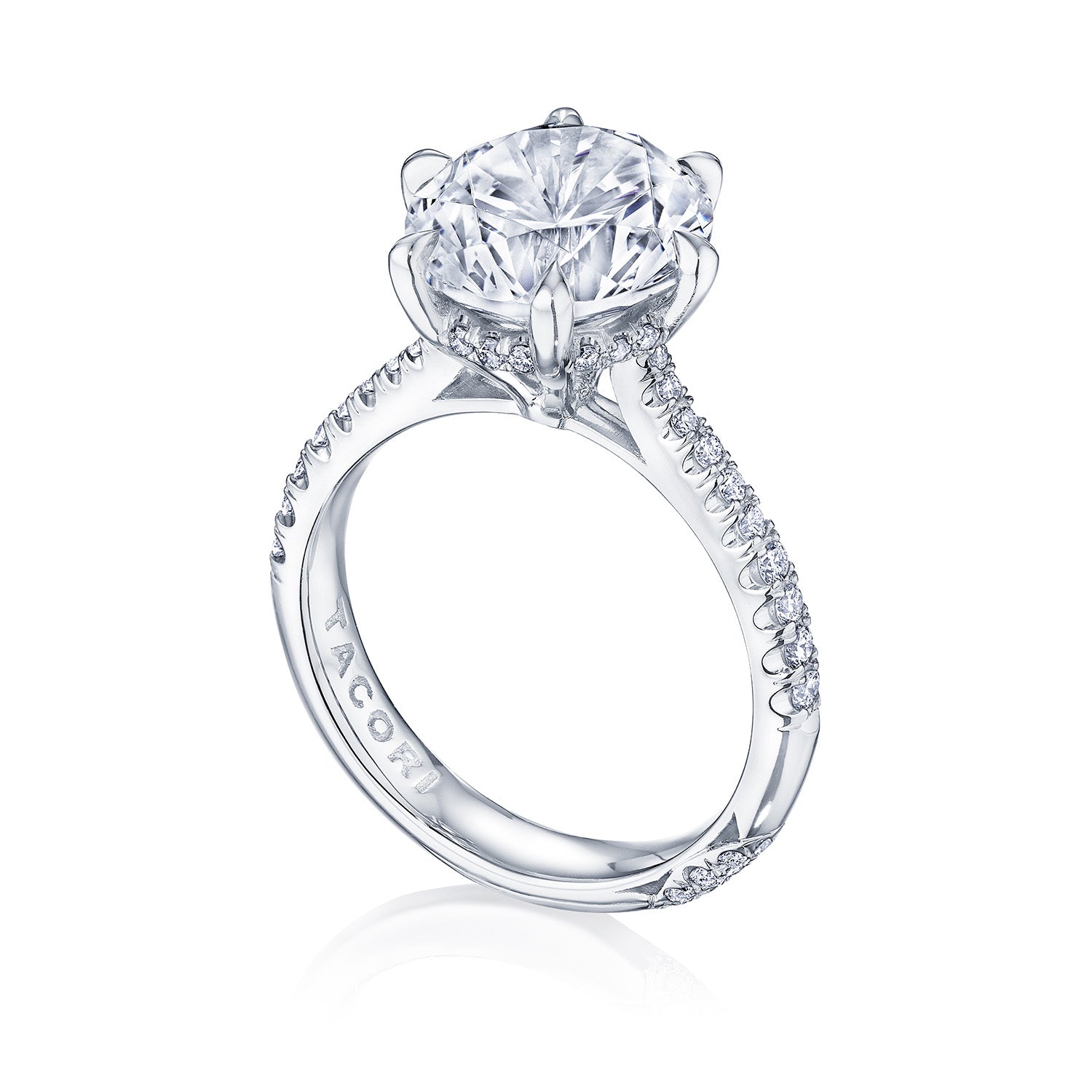 This stunning platinum solitaire engagement ring from the Tacori Founder's Collection RoyalT features a prominent round brilliant diamond center. It's elegantly enhanced by detailed side accents and smaller diamonds adorning the band, with expert craftsmanship by Tacori gemologists, showcasing an engraved logo inside.
