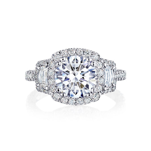 The Tacori Petite Crescent Royal T Platinum Round Brilliant Three Stone Halo Semi Mount with Diamond Side Stone Engagement Ring is meticulously crafted by Tacori gemologists. Featuring a large round center stone encircled by a halo of smaller diamonds, the band also includes additional diamonds and a geometric motif, adding to its intricate design. The ring is showcased against a white background.