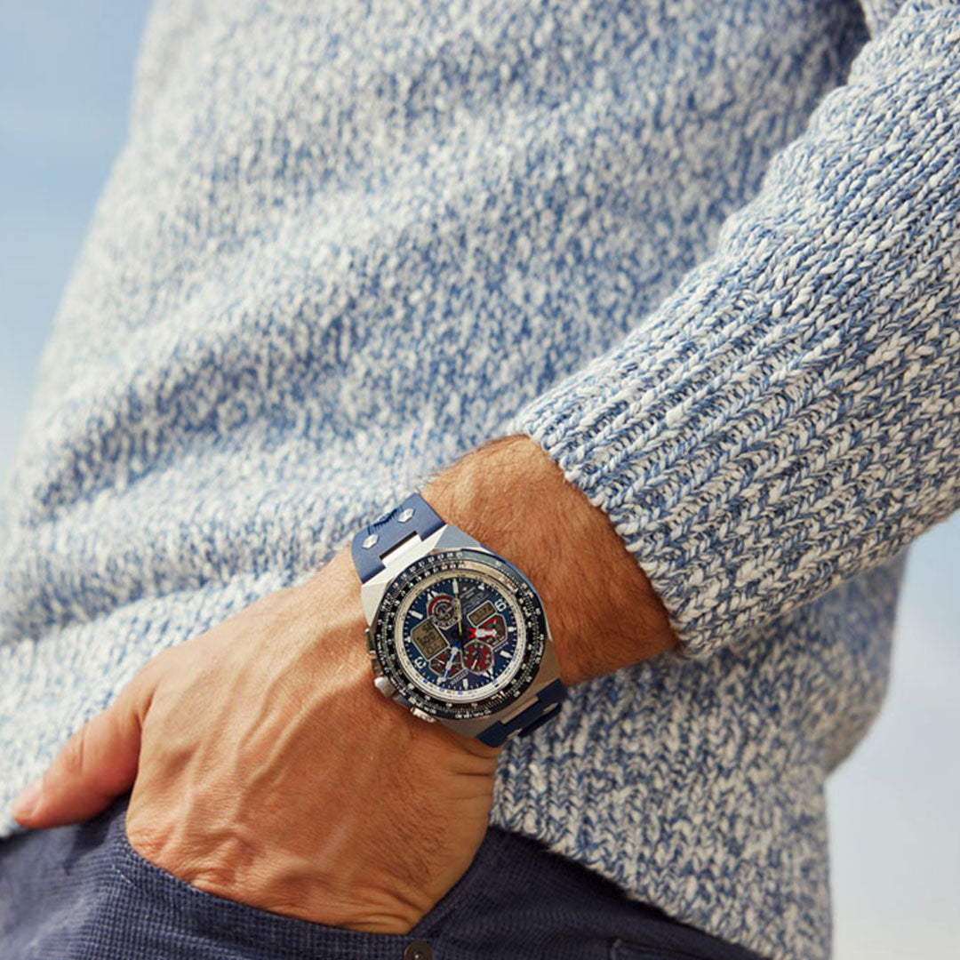 A person wearing a blue and white textured sweater with their right hand in a pocket is sporting a CITIZEN Promaster Sikorsky Eco-Drive 46mm watch, featuring an intricate design. The background is softly blurred.