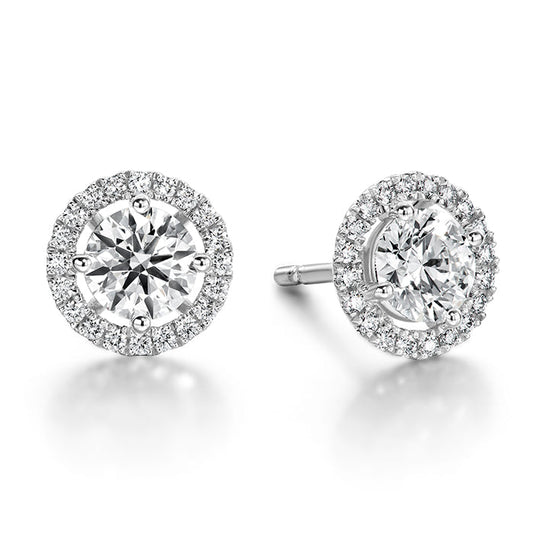 The Hearts On Fire Joy 18K White Gold Stud Earrings showcase a pair of round diamonds at their center, each surrounded by a halo of smaller diamonds set in exquisite 18 Karat White Gold. This design creates an enchanting, sparkling effect that exudes elegance.